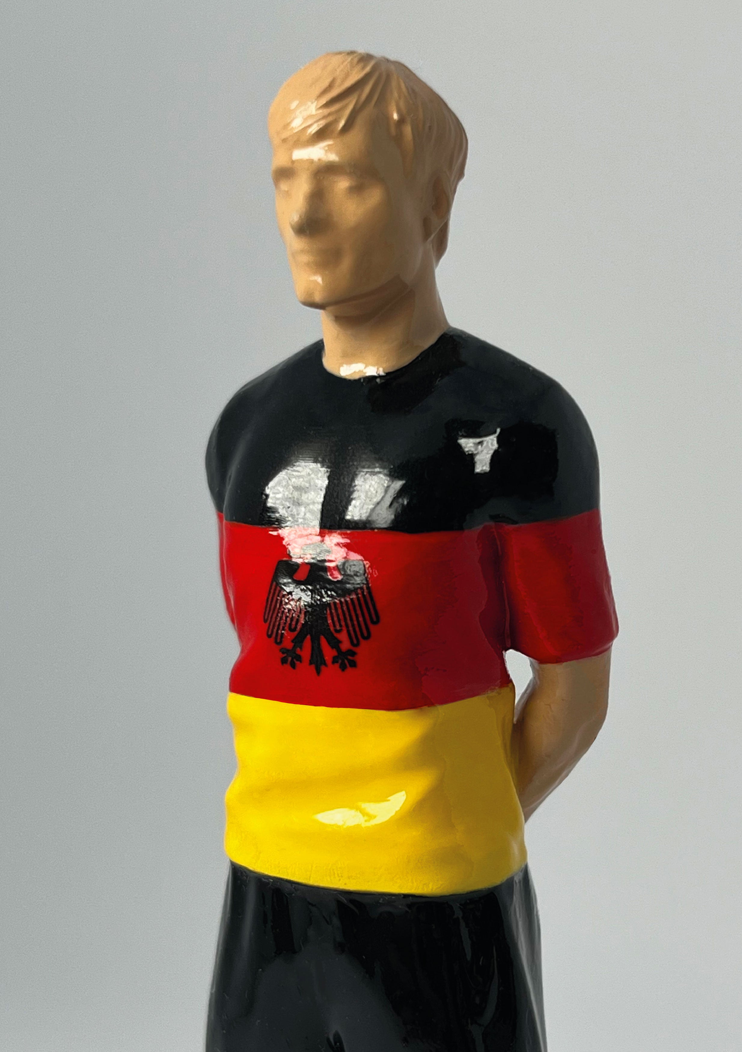 Figurine de collection Match Day FC équipe d'Allemagne, maillot noir rouge or à l'aigle, vue de profil.
